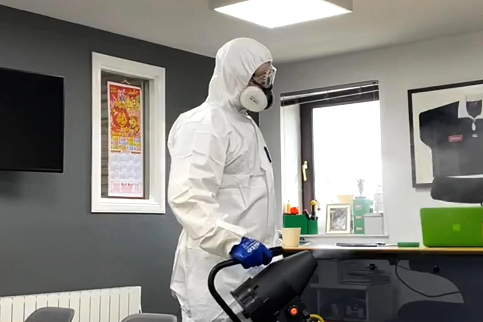 man wearing a cleaning suit doing a deep clean