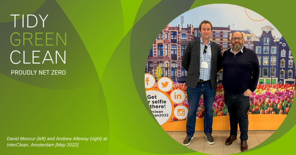 Two men at InterClean event, Amsterdam, with tulip backdrop.
