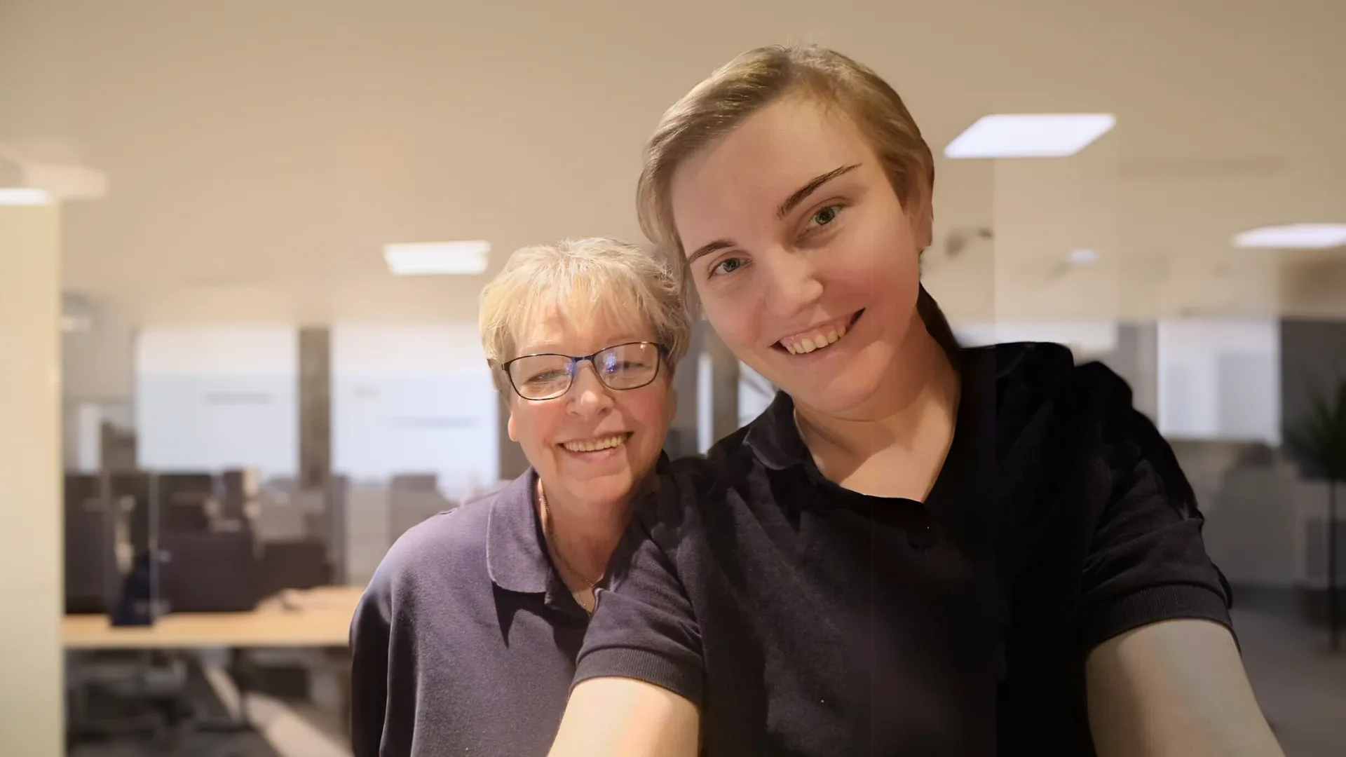 Two smiling people taking a selfie in the office.