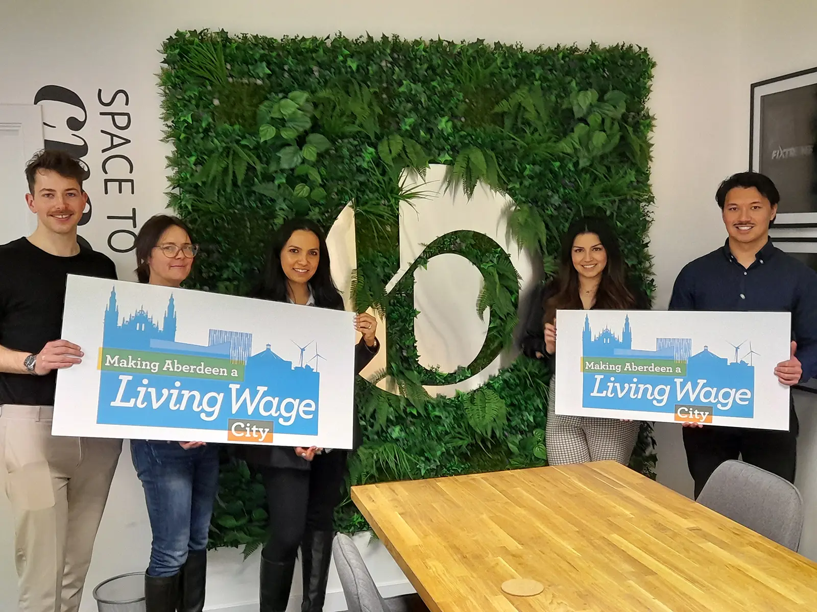 people holding a sign of promoting making aberdeen a living wage city
