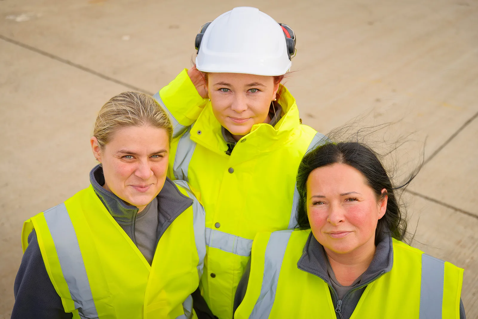 women workers wearing a hard hat and green jackets