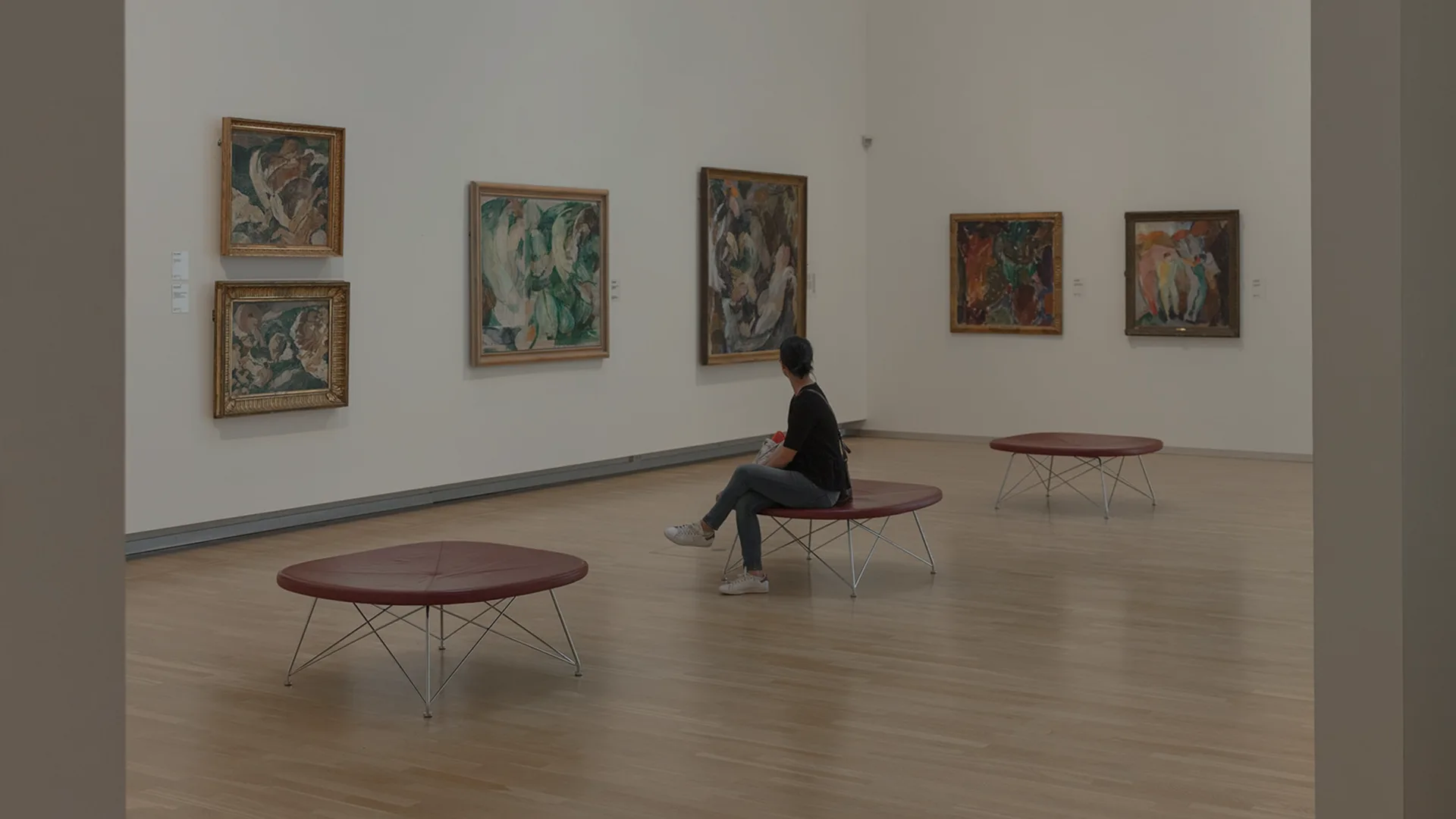 a woman sitting down looking at art pieces inside a gallery