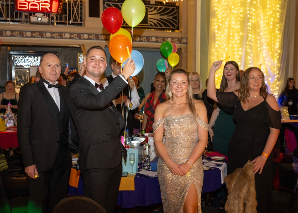 People celebrating at a formal event with balloons.
