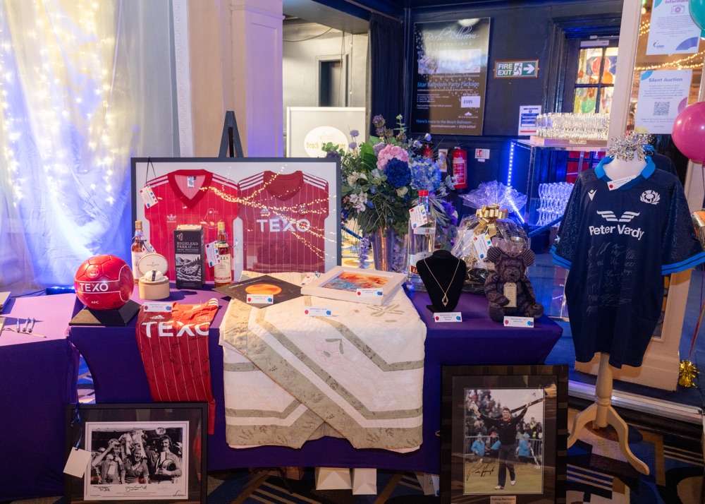 Charity auction display with sports memorabilia and gifts.